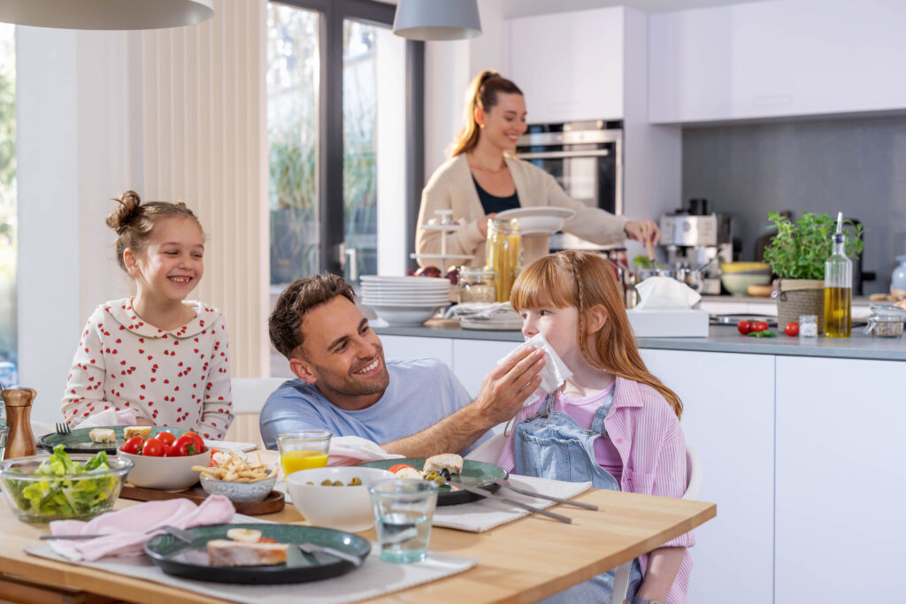 Familie am Esstisch mit Kuechenrolle